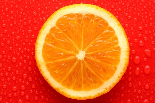 Slice of orange with drop on red background