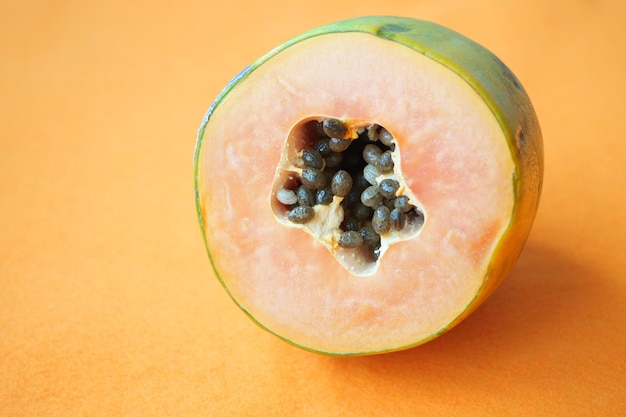 Slice of papaya on orange background