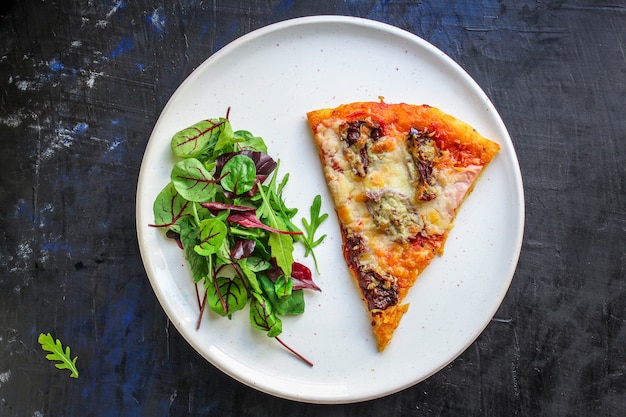 slice of pizza and salad leaves in a plate