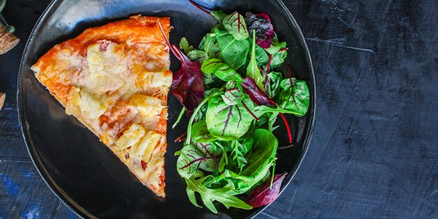 slice of pizza and salad leaves in a plate