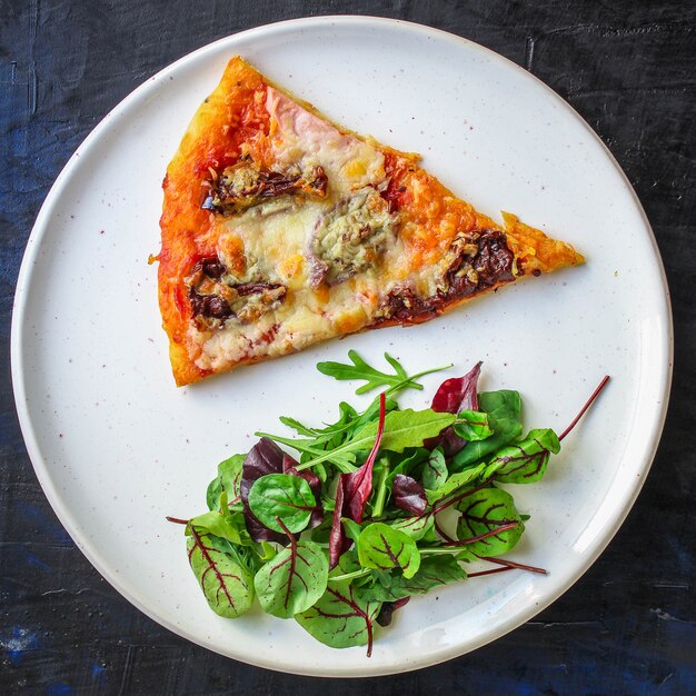 slice of pizza and salad leaves in a plate