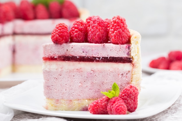 Slice of raspberry mousse cake with berry jelly and whipped cream 