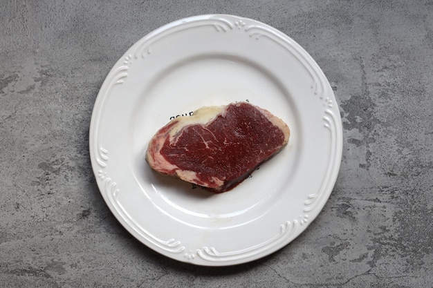 Кусок сырого говяжьего мяса на белой тарелке