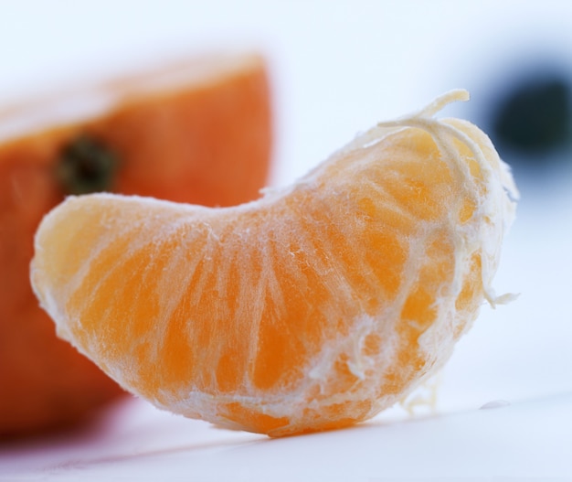 Slice of a ripe tangerine on white