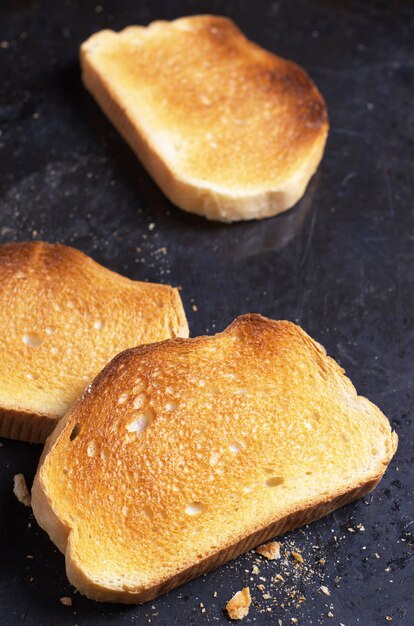 Slice of roasted white bread on black background close up