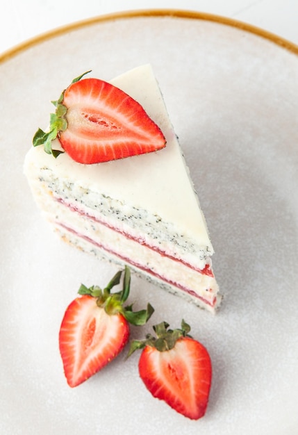 a slice of strawberry cake on a gray plate decorated with strawberries view from above on a white background