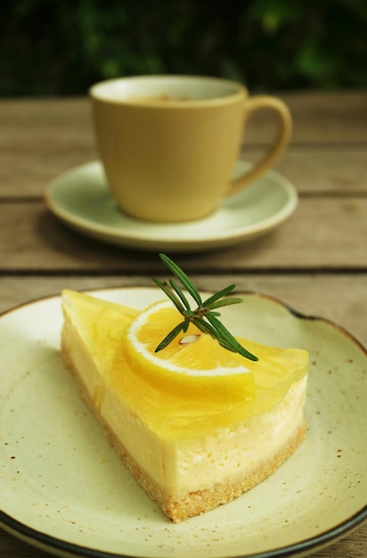 Slice of sweet and tart lemon cream cheese pie with blurry coffee cup in the backdrop