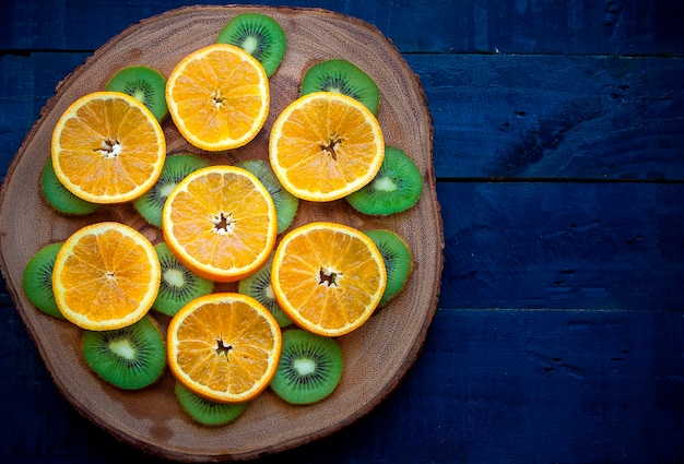 Slice of tangerines and kiwi on wooden slice