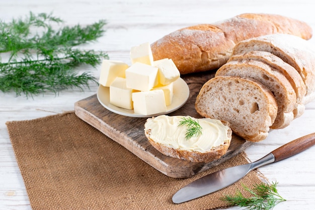 Slice of tasty bread with butter on a white wooden table with copy space