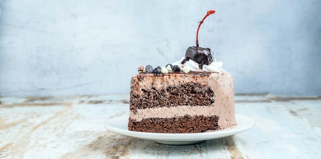 Кусочек вкусного домашнего шоколадного торта на тарелке на деревянном фоне