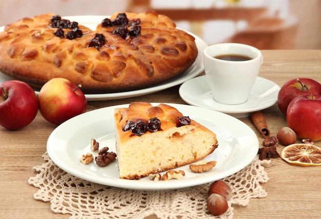 Slice of tasty homemade pie with jam and apples and cup of coffee on wooden table