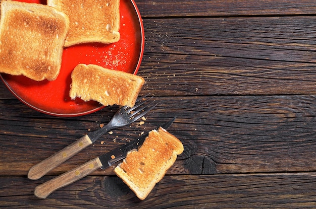 Slice of toasted bread fork and knife on old wooden table top view Space for text