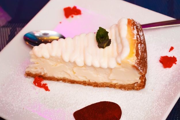 Нарезать ванильный пирог сливочным кремом глазурью в тарелку. Торт с бисквитом и сливками. Съемка крупным планом.