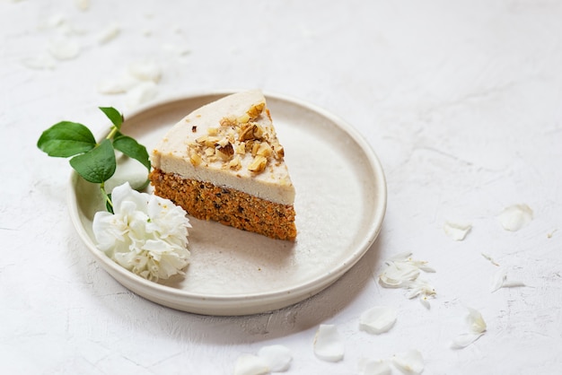 Fetta di torta di carote vegana con crema di cocco e noci