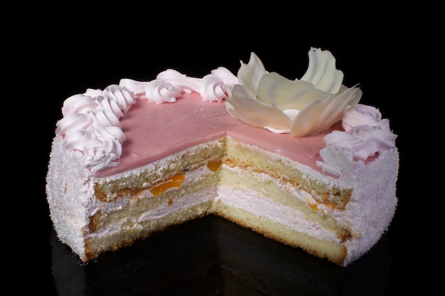 Slice of white cake with pink icing on a black background