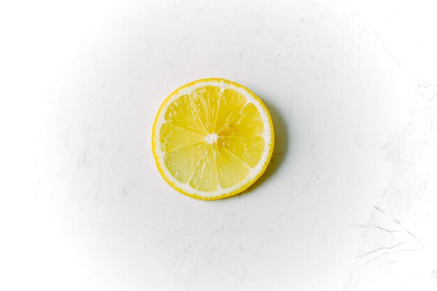 밝은 대리석 배경에 노란색 즙이 많은 레몬 한 조각