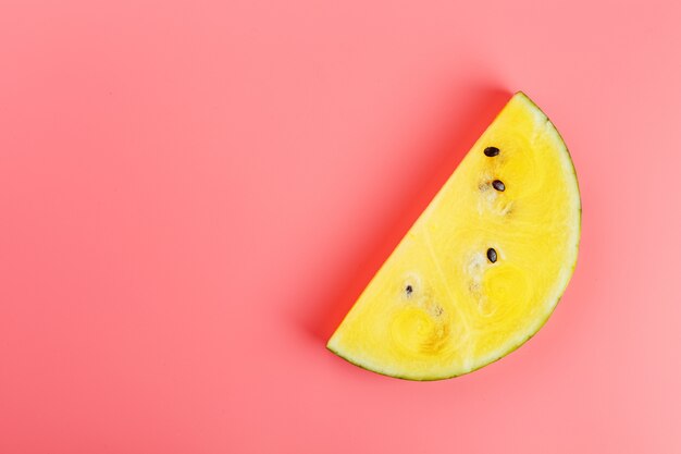 Photo slice of yellow watermelon on pink