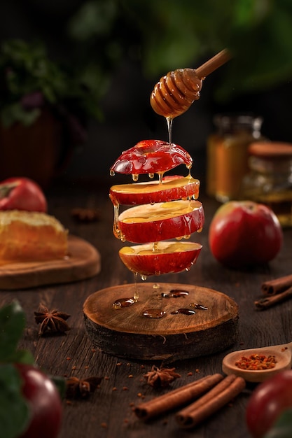 Photo sliced apple with honey drops levitating above wooden table