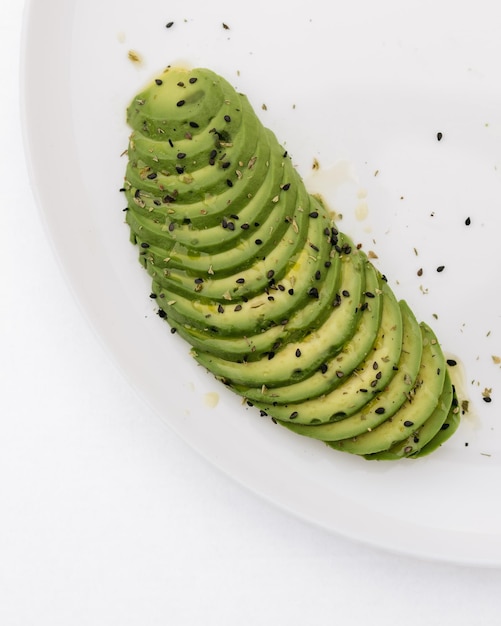 Foto fan d'avocado tagliato in fette e guarnito con semi di sesamo su un piatto bianco