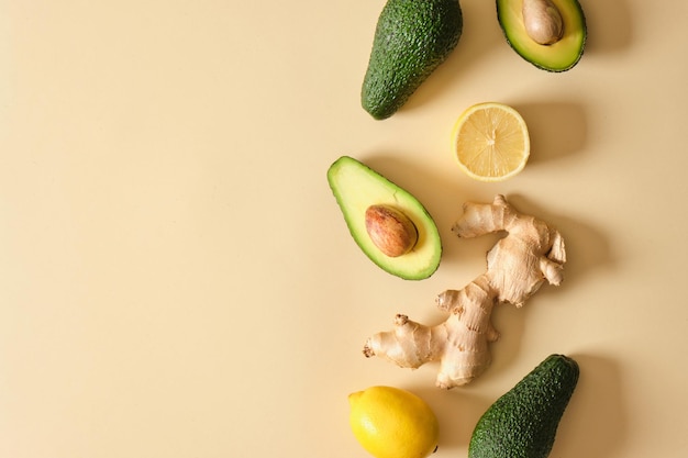 Sliced avocado lemon and ginger on beige background