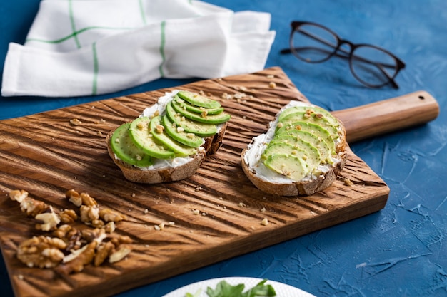 Sliced avocado on toast bread with nuts. Breakfast and healthy food concept.