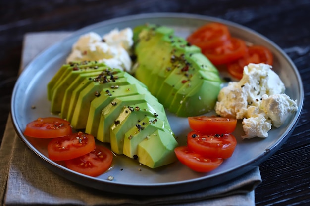 Sliced avocado with cream cheese and tomatoes on a plate Selective focus macro Keto diet