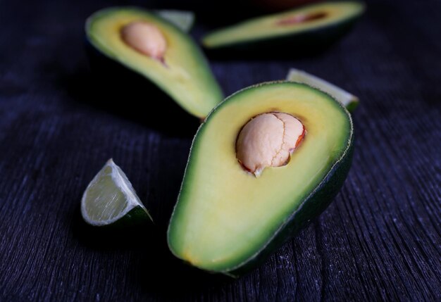 Sliced avocado with pieces of lime on wooden background