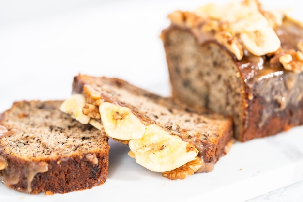 Il pane alle noci di banana affettato ha spruzzato caramello fatto in casa su un tagliere di marmo.