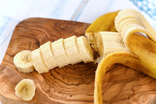 Sliced banana on wooden kitchen board