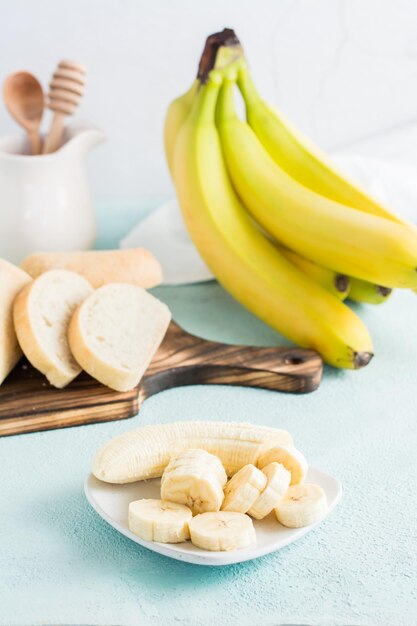 Sliced bananas on a plate prepared for making banana bread on the table Homemade baking Vertical view