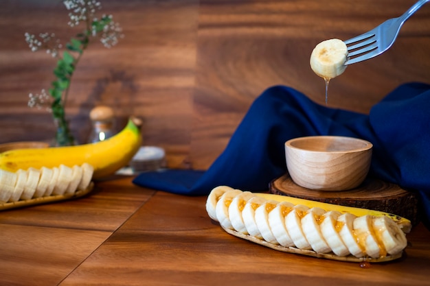 Photo sliced bananas with honey on a wooden table