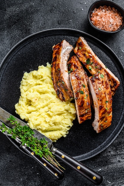 Sliced BBQ grilled pork rack spare ribs on a plate with mash potato. 