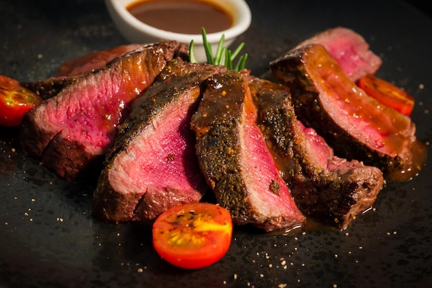 Sliced beef steak on black plate food concept vintage tone