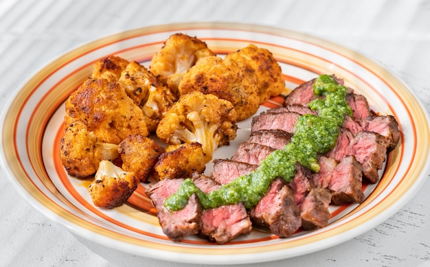 Sliced beef steak garnished with baked cauliflower florets