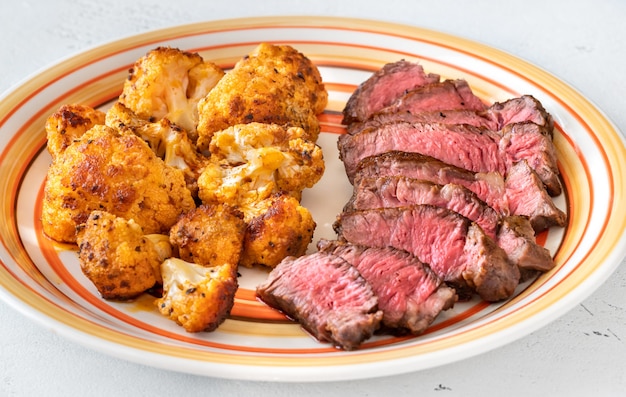 Sliced beef steak garnished with baked cauliflower florets