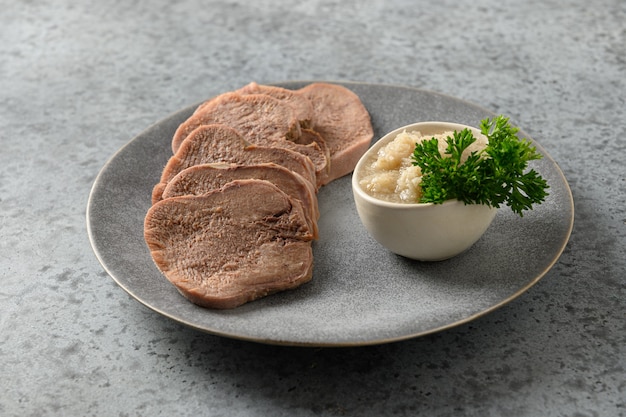 Sliced beef tongue with horseradish sauce on grey