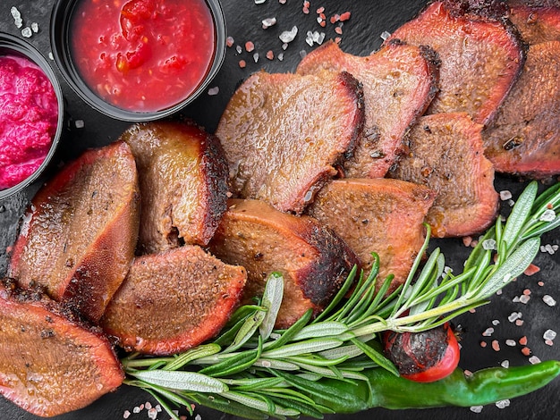 Photo sliced beef tongue with sauces directly above close up