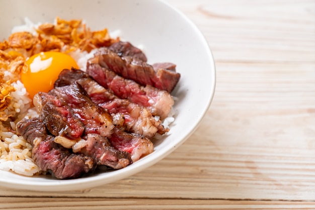 Photo sliced beef on topped rice bowl with egg