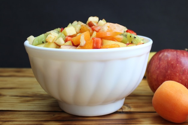 Le bacche e la frutta a fette sono su un piatto per preparare un'insalata dietetica. colazione luminosa a basso contenuto calorico per dimagrire su un tavolo di legno.