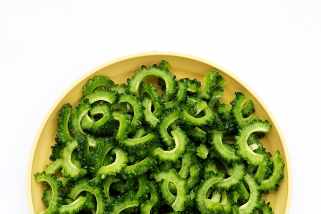 Sliced bitter gourd in yellow plate white background.