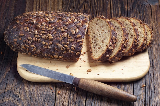 Sliced black bread with sunflower seeds on cutting board