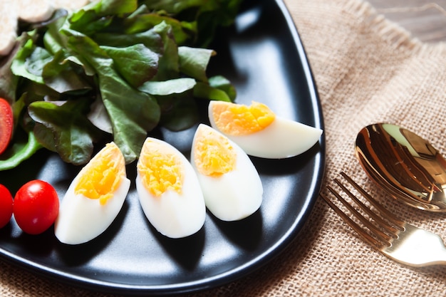 Photo sliced boiled eggs and vegetables on black plate