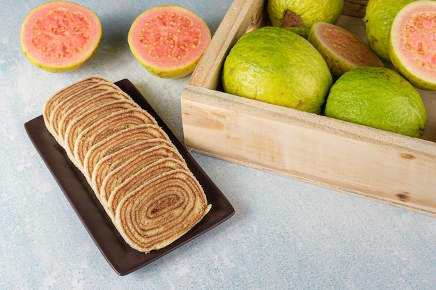 Sliced bolo de rolo (roll cake) next to a box with guavas.