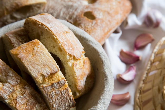 Sliced bread in a basket with garlic cloves in the background.