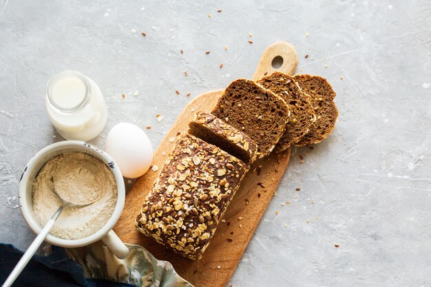 Нарезанный хлеб на доске с молоком. Вкусный, красивый домашний хлеб с зернами. Домашняя выпечка. Безглютеновая выпечка. Черный хлеб с банкой молока. Домашний хлеб