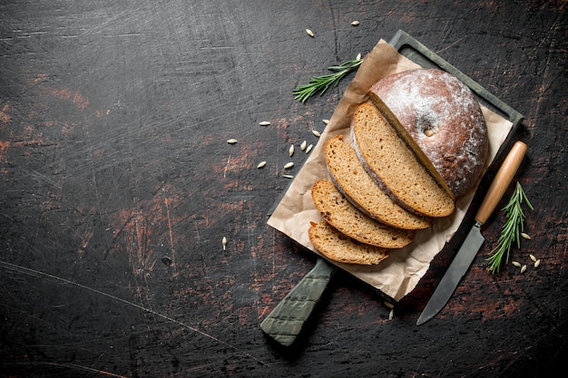 Sliced bread on a cutting Board with a knife and rosemary