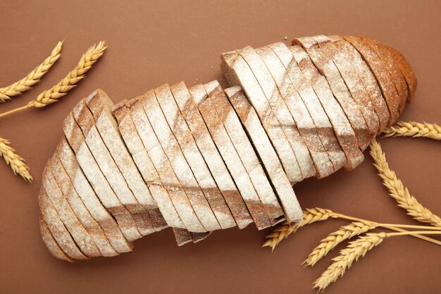 Photo sliced bread ears of wheat on brown background homemade bakery concept