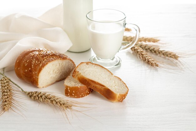 Sliced bread ears of wheat milk on a white wooden table Symbols of Jewish holiday Shavuot