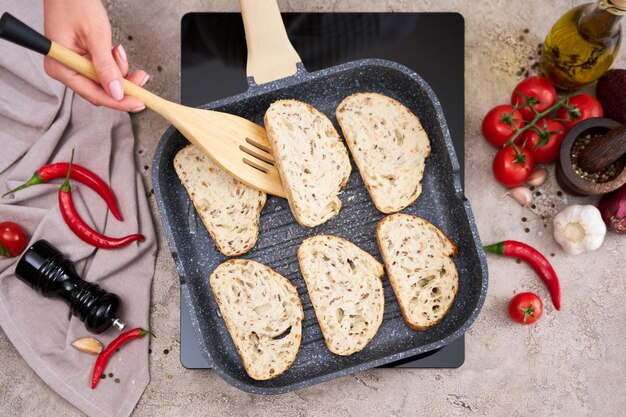 Sliced bread fried on grill frying pan at domestic kitchen