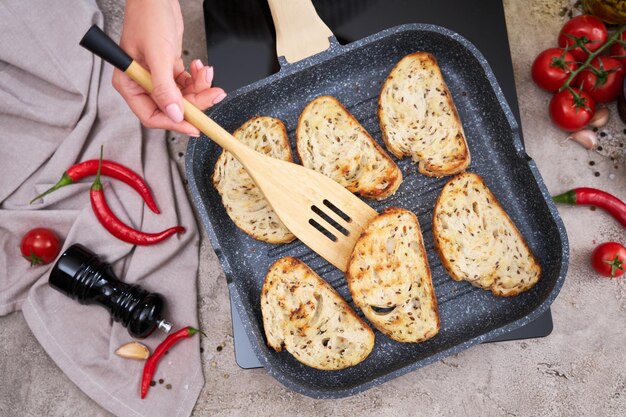 Sliced bread fried on grill frying pan at domestic kitchen